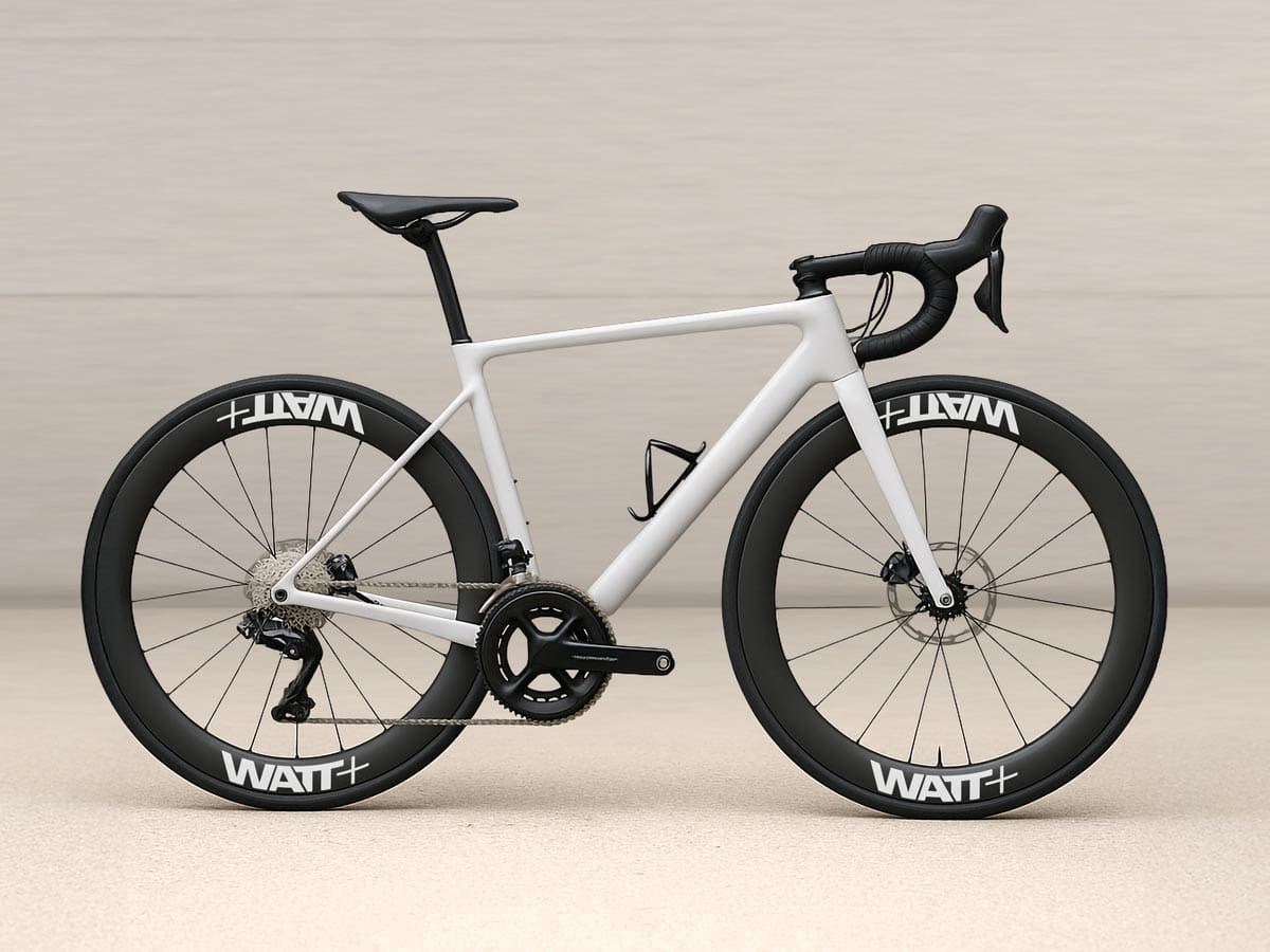 Weißes Rennrad mit hohen Carbon-Laufrädern, auf denen Felgenaufkleber mit der Aufschrift „WATT+“ angebracht sind, vor hellem Hintergrund.